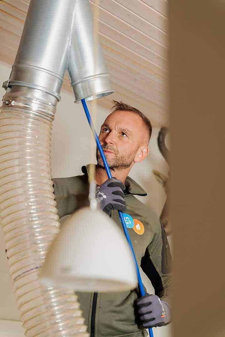 Montør fører rensebørsten op i ventilationskanalen